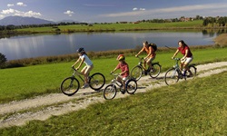Eine Familie imt zwei Kindern radelt auf einem weiß geschotterten Radweg am Staffelsee entlang.