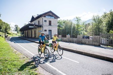 Zwei Radler fahren auf dem Alpe-Adria-Radweg am Bahnhof von Tarvis vorbei.