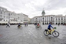 Drei Radler überqueren eine Piazza in Triest.