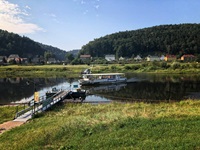 Ein kleines Schiff auf der Donau fährt zu einem Holzsteg