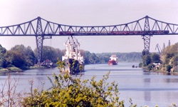 Zwei Schiffe auf dem Nord-Ostsee-Kanal fahren unter der Rendsburger Eisenbahnhochbrücke durch