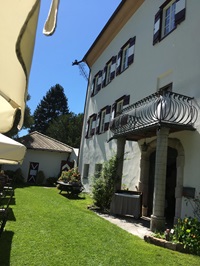 Ein gepflegter Rasen vor einem Haus, dessen Eingang mit zwei Säulen und überdacht ist