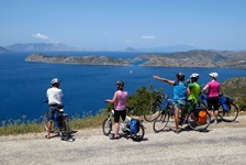 Fünf Radfahrer haben auf einer an der Lykischen Küste entlang führenden Straße angehalten und genießen den Ausblick auf das Meer.