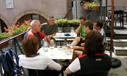 Eine Gruppe Radler sitzt an einem Tisch auf einer Terrasse eines Restaurants und trinkt kühle Getränke