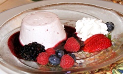 Nachtischteller mit Panna cotta, verschiedenen Beeren und einem Früchtespiegel und Sahnehaube