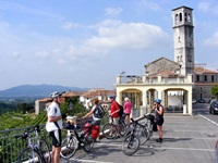 Eine Radlergruppe macht eine Pause auf dem Parkplatz der Kirche Santa Maria sopra Minerva in Assisi