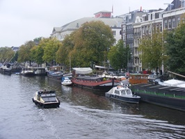 Blick über die Amstel mit angelegten Schiffen zur Promenade in Amsterdam