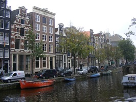 Blick über einen Kanal mit angelegten Booten und Häuserfassaden in Amsterdam