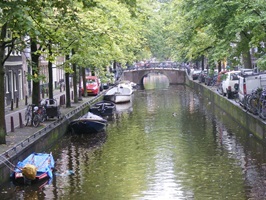 Blick über den Kanal mit angelegten Booten und der Promenade in Amsterdam