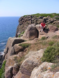 Ein Radler sitzt auf einem Felsen und genießt den herrlichen Ausblick über das Meer.