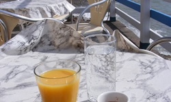 Ein Glas Orangensaft, ein Glas Wasser und ein Espresso auf dem Tisch eines italienischen Straßencafés.