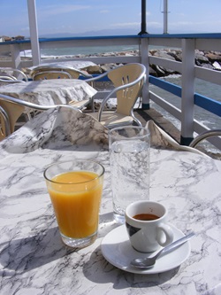 Ein Glas Orangensaft, ein Glas Wasser und ein Espresso auf dem Tisch eines italienischen Straßencafés.