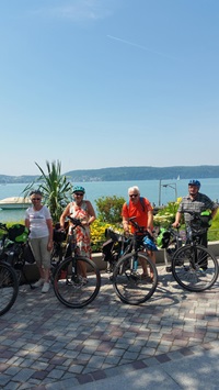 Eine Radlergruppe steht an einer Promenade am Bodensee und blickt in die Kamera