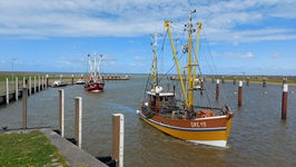 Zwei Boote fahren in einen Hafen der Ostsee auf der Radreise durch Ostfriesland