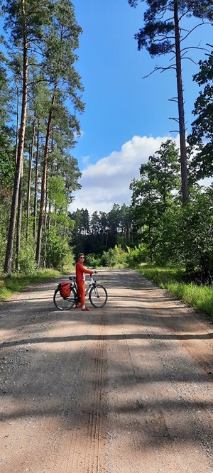 Eine Radfahrerin steht mit ihrem Rad auf einem Waldweg bei der Radreise Danzig, Ermland und Masuren