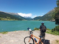 Ein Radler betrachtet das herrliche Bergpanorama rund um den Reschensee.