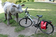 Ein Fahrrad steht neben einer Holzskupltur in Form einer Kuh