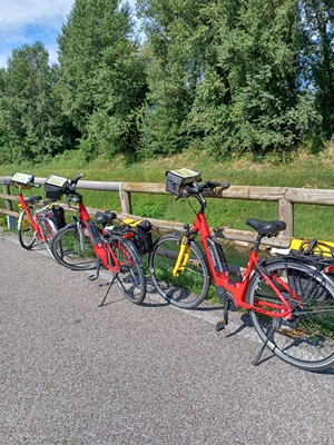 Drei rote Fahrräder stehen an einem Holzzaun auf einem asphaltieren Weg bei der Radreise von Bozen über Verona nach Venedig