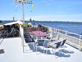 Blick zum Sonnedeck mit einem Tisch und dazugehörigen Stühlen sowie den abgestellten und abgedeckten Leihrädern auf der MS Flora