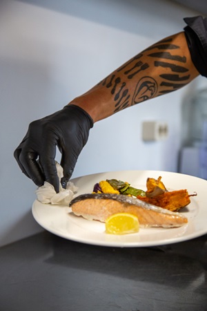 Ein mit Fisch angerichteter Teller wird abgewischt