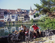 Drei Radler machen bei Büren eine Trinkpause am Ufer der Aare.