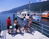 Vier Radler warten am Bielersee darauf, an Bord der MS Stadt Biel gehen zu können.