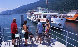 Vier Radler warten am Bielersee darauf, an Bord der MS Stadt Biel gehen zu können.