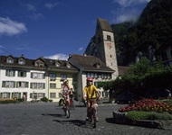 Drei Radfahrer lassen die Kirche von Unterseen hinter sich.