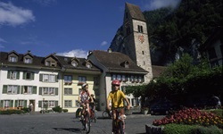 Drei Radfahrer lassen die Kirche von Unterseen hinter sich.