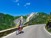 Ein Radler fährt bei der Abfahrt von einem Pass bei den Marmorsteinbrüchen von Carrara durch eine wunderschöne Berglandschaft.