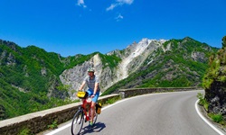 Ein Radler fährt bei der Abfahrt von einem Pass bei den Marmorsteinbrüchen von Carrara durch eine wunderschöne Berglandschaft.