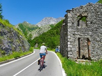 Ein Radler fährt auf einer Passstraße bei den Marmorsteinbrüchen von Carrara an einem verfallenen Haus vorbei.