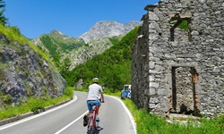 Ein Radler fährt auf einer Passstraße bei den Marmorsteinbrüchen von Carrara an einem verfallenen Haus vorbei.