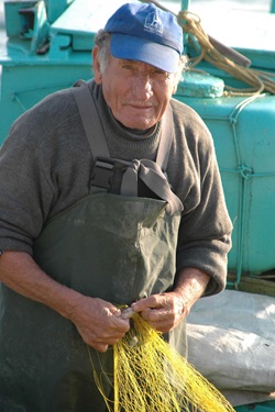 Ein Fischer der Griechischen Ägäis bei der Arbeit mit seinem gelben Fangnetz