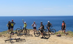 Eine Gruppe Radler steht an einer Steilküste in der Südlichen Ägäis von Griechenland
