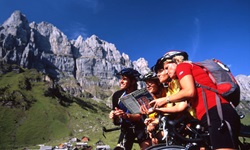 Vier Radler beugen sich vor einer herrlichen Alpenkulisse über ihre Reiseunterlagen.