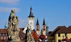 Steinfiguren auf der Alten Mainbrücke in Würzburg. Im Hintergrund sind die Doppeltürme des Doms zu erkennen.