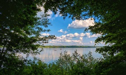 Der Ammersee durch ein von Bäumen gebildetes Fenster gesehen.