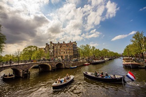 Blick über den Kanal mit Booten und zu den typischen Häusern von Amsterdam