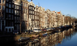 Der Kanal mit angelegten Booten und der typisch aneinandergebauten Häuser in Amsterdam