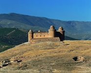 Blick auf eine kleine Burg mit zwei Türmen, die ein Kuppeldach haben, bei Granada in Andalusien