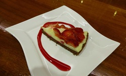 Ein auf einem Teller angerichtetes Stück Erdbeerkuchen mit Vanillepudding und Erdbeersauce.