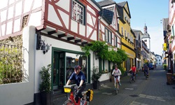 Einige Radler durchqueren ein schmuckes, von Fachwerkhäusern geprägtes Städtchen.