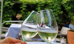 Zwei zu jeweils einem Drittel mit Weißwein gefüllte Weingläser werden aneinandergestoßen.