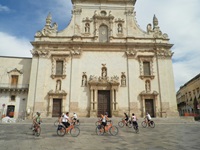 Eine Gruppe von Radlern bestaunt ein historisches Bauwerk.