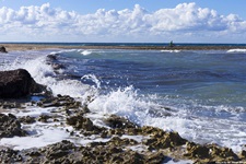 Schäumende Gischt an einer Felsküste im Salento.