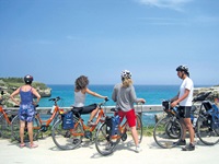 Eine Radlergruppe macht an einer Küstenstraße im Salento Pause und genießt den herrlichen Ausblick auf das Meer.