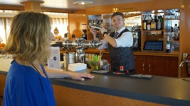 Ein freundlicher Barkeeper bereitet an der Bar der MS Arlene II einen Drink zu.