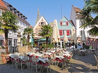 Stühle und Sonnenschirme vor einem Restaurant in der Fußgängerzone von Bad Dürkheim.