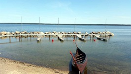 Ein kleines Boot ist an einem Holzsteg an der baltischen Ostseeküste vertäut.